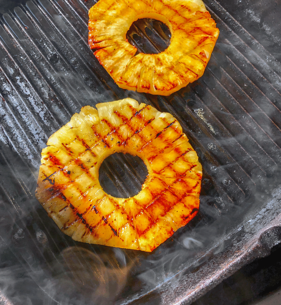 Hawaiian BBQ Chicken Sandwich Grilled pineapple on a smoky grill pan ready for the Hawaiian BBQ chicken sandwich.